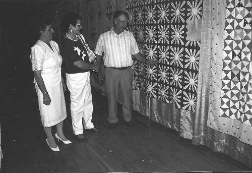 Mr. and Mrs. Claude Lenzmeier and Matheal Schneider with St. Hubert's name quilt.